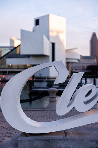 Cleveland, OH, USA - December 20, 2023: A portion of the Cleveland script sign at Voinovich Bicentennial Park with the Rock and Roll Hall of Fame museum in the background