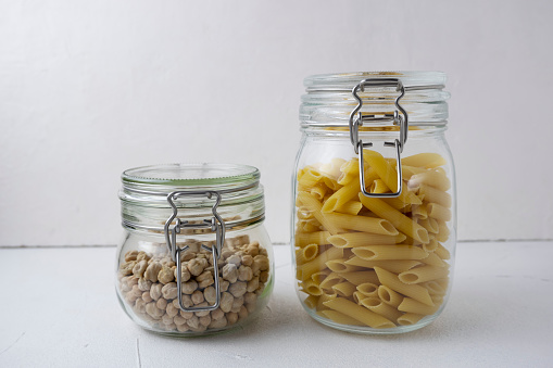 A set of cereals in a glass jar on a light background, chickpeas, oatmeal, pasta, healthy eating. Concept of food, healthy eating and diet.