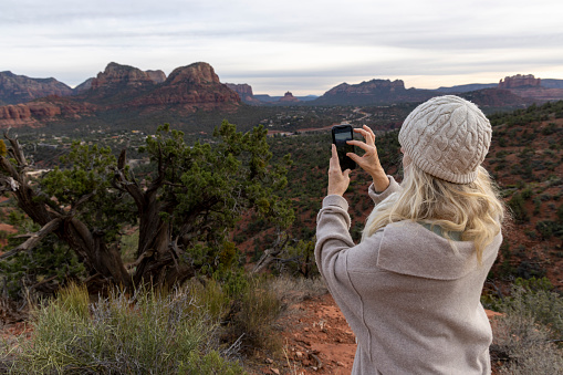 Mature woman takes photo of desert landscape from elevated landscape