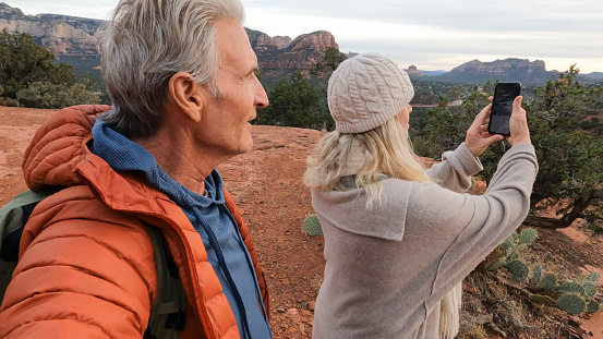 Mature couple take photo from viewpoint in desert landscape