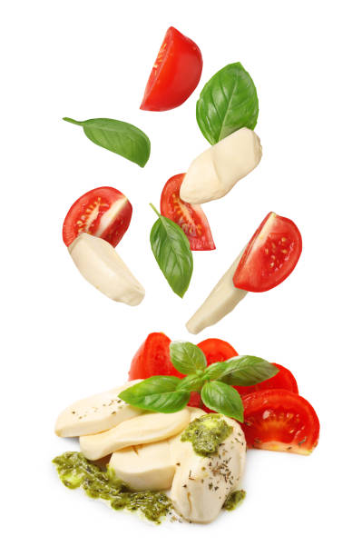 istock Making Caprese salad. Fresh tomatoes. mozzarella cheese and basil leaves falling against white background 1885448982