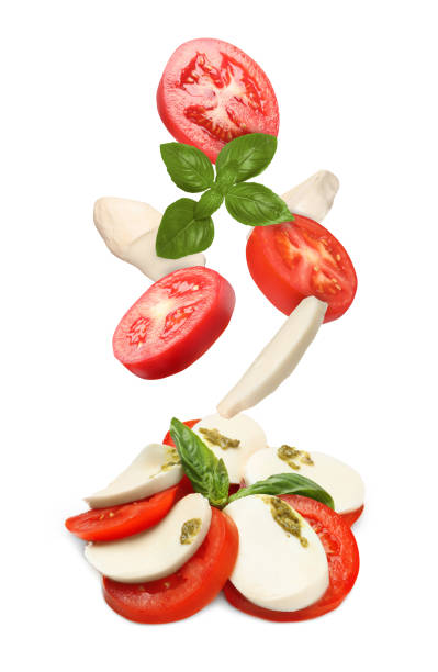 istock Making Caprese salad. Fresh tomatoes. mozzarella cheese and basil leaves falling against white background 1885448984