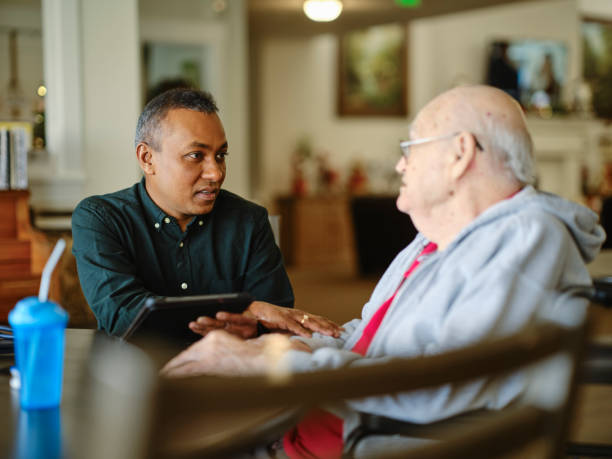 Senior Citizen Care A healthcare worker attending to a senior citizen resident in a senior care living facility. community outreach stock pictures, royalty-free photos & images