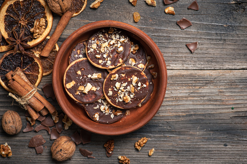 Homemade biscuit with chocolate and walnuts in a brown bowl on a wooden background. From above