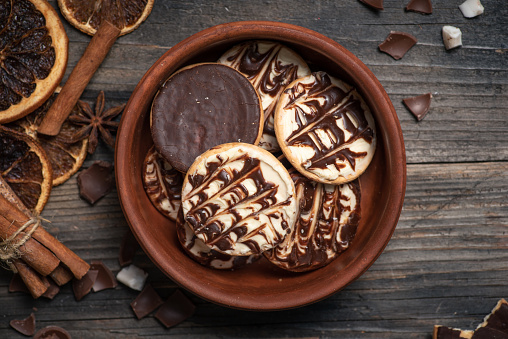 Homemade biscuit with white and dark chocolate in a brown bowl on a wooden background. From above