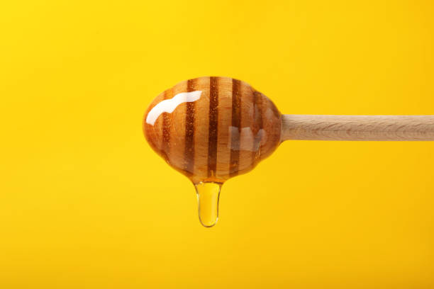 istock Pouring honey from dipper against yellow background, closeup 1885468479