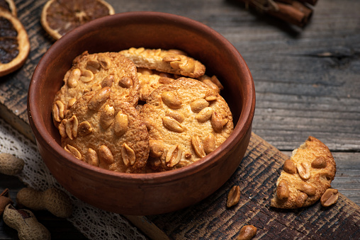 Homemade biscuit with peanuts in a bowl on a rustic wooden background. Crunchy dessert