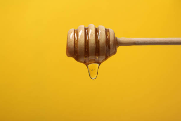 istock Pouring honey from dipper against yellow background, closeup. Space for text 1885469528