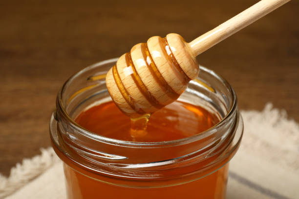 istock Pouring honey from dipper into jar at table, closeup 1885469529
