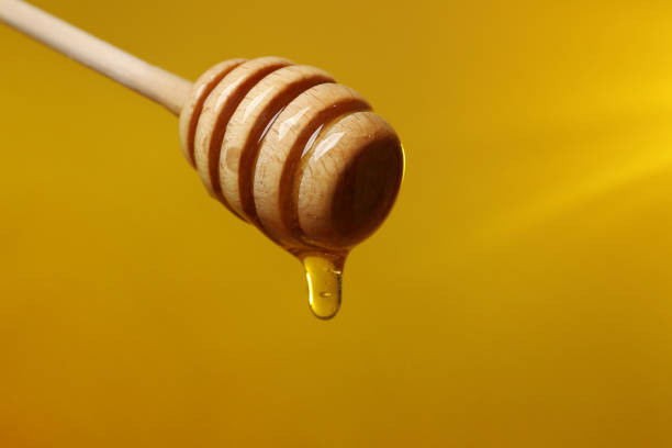 istock Pouring honey from dipper against golden background, closeup. Space for text 1885471111