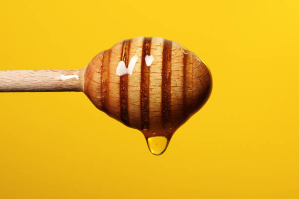 istock Pouring honey from dipper against golden background, closeup. Space for text 1885473201