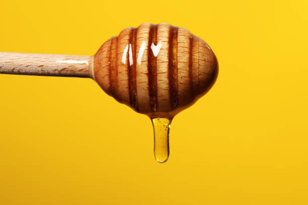 istock Pouring honey from dipper against golden background, closeup. Space for text 1885473202