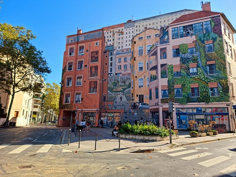 The mural painting “Mur des Canuts” in Lyon. This is Europe’s largest and biggest mural painting covering 1200 m2. It’s what the French call a “trompe l’oeil” (=optical illusion) and every thing you see on the wall is an illusion. The image shows the painted building captured during autumn season.