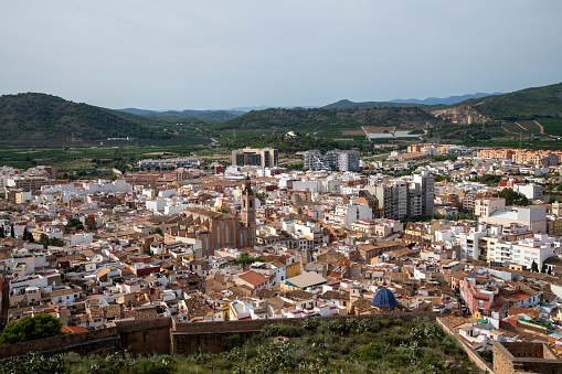 Sagunt, Valencia - Spain - 09-07-2021: Cityscape featuring an impressive church, mountains, and misty nature surrounding the city.