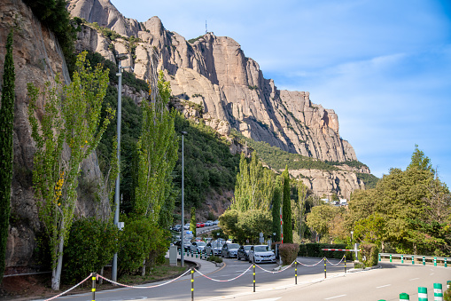 Montserrat, Barcelona Province - Spain - 29/10/2021: View of a long queue of cars before the entrance of Montserrat Monastery. Traffic jam below a mountain wall, access roads equipped with barriers and gates.
