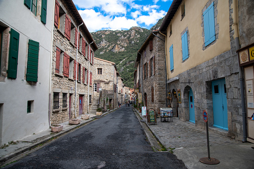 Villefranche de Conflent, Les Pyrenees catalanes - France - 21/10/2023: View of the streets of Villefranche de Conflent in France. Asphalted road lined with colorful shutters on historic buildings.