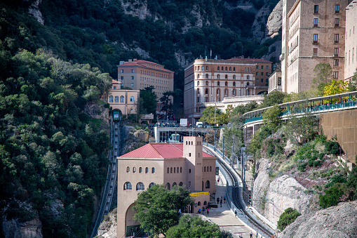 Montserrat, Barcelona - Spain - 10-29-2021: View of funicular and regular train stations at Montserrat Monastery, with tracks and buildings clearly visible.