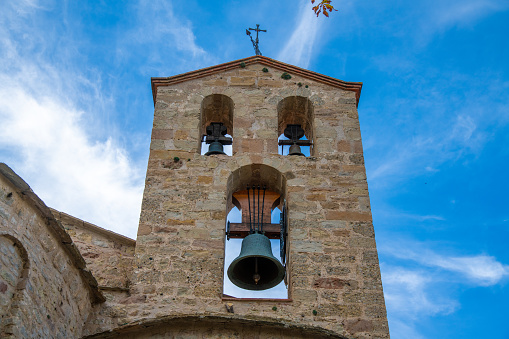 Montserrat, Province of Barcelona - Spain - 10-29-2021: Bells of Santa CecÃ­lia Church in Montserrat Mountain. The bells are located outside the church, consisting of one large bell and two small bells against a blue sky.