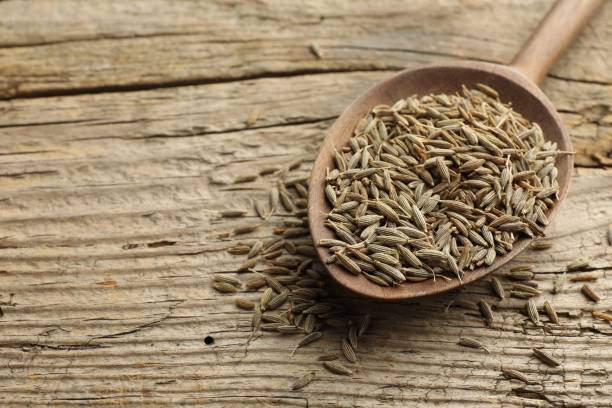 istock Spoon with caraway seeds on wooden table, closeup. Space for text 1885526550