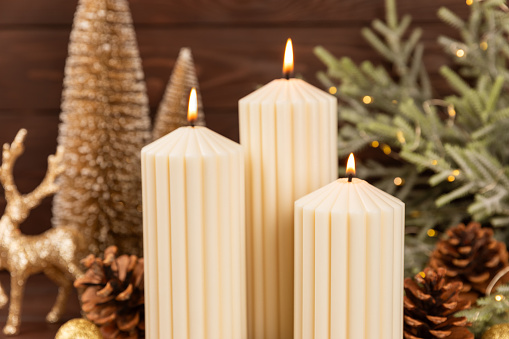 Christmas decoration with candle on texture background. New Year and Christmas candles. Cozy home decor. Burning candle and Christmas decoration. Christmas lights. Copy space.Holiday concept.