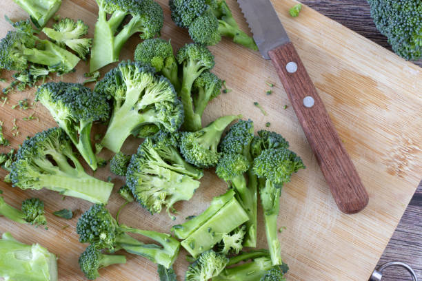 istock Fresh broccoli florets on a wooden cutting board with a knife, top view 1885569719