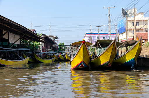 A captivating image showcasing the homes and boats along the canals and waterways of Bangkok. This scene reflects the traditional lifestyle and unique charm of the city's canal-side communities, where life is intimately tied to the water, and boats serve as a vital means of transport and livelihood.