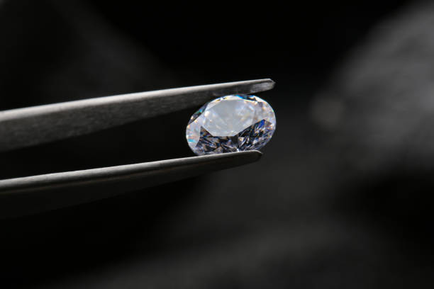 istock Tweezers with beautiful shiny diamond on dark background, closeup 1885591459