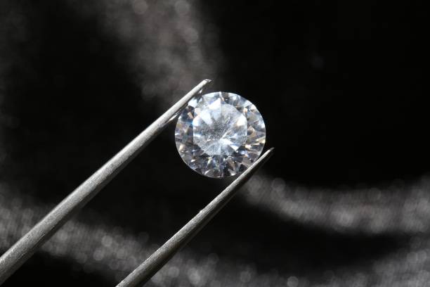 istock Tweezers with beautiful shiny diamond on dark background, closeup 1885592502