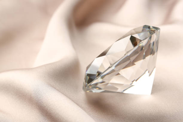 istock Beautiful shiny diamond on beige silky fabric, closeup. Space for text 1885592514