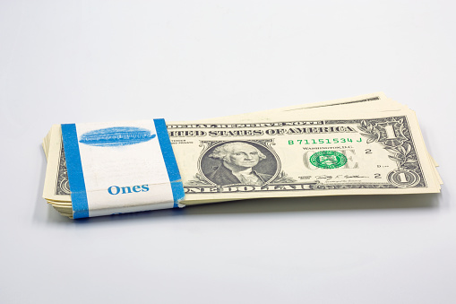 stack of one dollar bills in bank packaging closeup on white