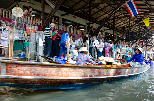 29th January, 2016 - Bangkok, Thailand: Bustling with activity, the floating market in Bangkok is a vibrant mosaic of colors and sounds. Market traders skillfully navigate their boats, laden with a variety of local produce and goods, while boat excursion operators guide tourists and local buyers through the waterways. The scene is a lively showcase of traditional Thai commerce and culture, with visitors engaging in the unique experience of shopping on water.