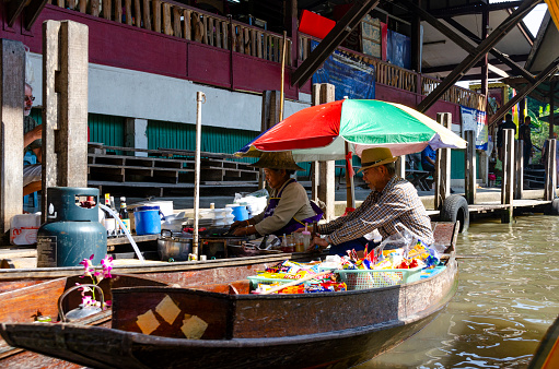 Asian Food vendor at the Damnoen Saduak Floating Market near Bangkok. Lady is selling traditional thai food from her boat.