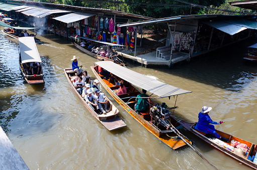 29th January, 2016 - Bangkok, Thailand: Bustling with activity, the floating market in Bangkok is a vibrant mosaic of colors and sounds. Market traders skillfully navigate their boats, laden with a variety of local produce and goods, while boat excursion operators guide tourists and local buyers through the waterways. The scene is a lively showcase of traditional Thai commerce and culture, with visitors engaging in the unique experience of shopping on water.