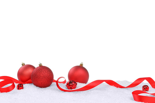 Beautiful red Christmas balls, ribbon and sleigh bells on snow against white background