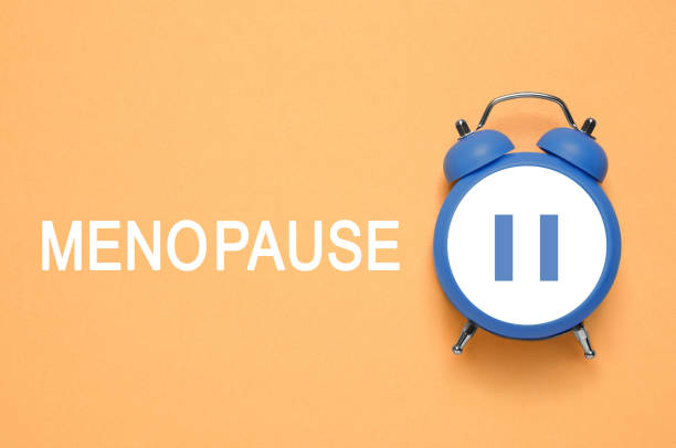 istock Menopause word and alarm clock with pause symbol on orange background, top view 1885686933