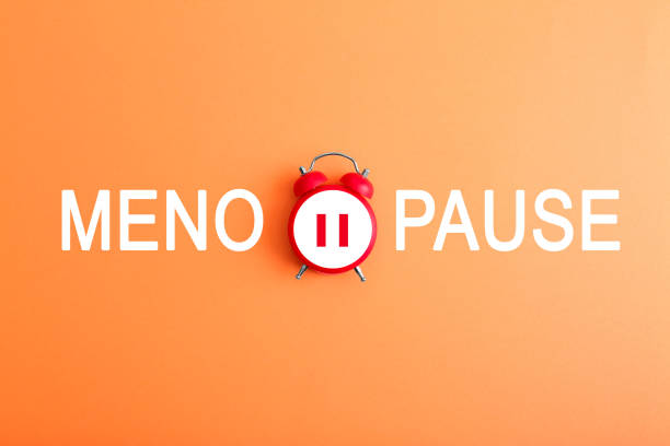 istock Menopause word and alarm clock with pause symbol on orange background, top view 1885686947
