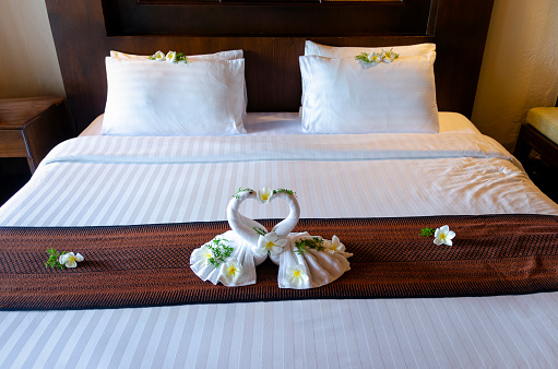 A charming image of towel art in a Thai hotel room, where towels are creatively folded into the shape of elegant swans. This delicate and artistic touch adds a sense of luxury and care to the guest experience, reflecting the attention to detail and hospitality Thailand is renowned for.