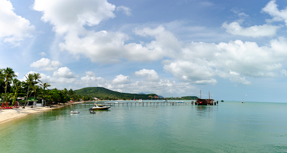 A serene image of a jetty in Koh Phangan, with boats moored in calm waters. This picturesque scene captures the tranquil beauty of the island, showcasing the simplicity of seaside life amidst Thailand's famous tropical paradise.