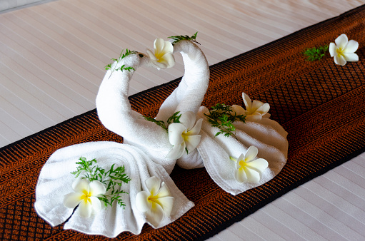 A charming image of towel art in a Thai hotel room, where towels are creatively folded into the shape of elegant swans. This delicate and artistic touch adds a sense of luxury and care to the guest experience, reflecting the attention to detail and hospitality Thailand is renowned for.