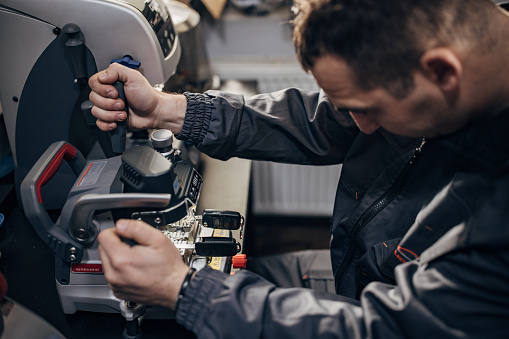 One man, professional key cutter, making car keys copies on modern machine.