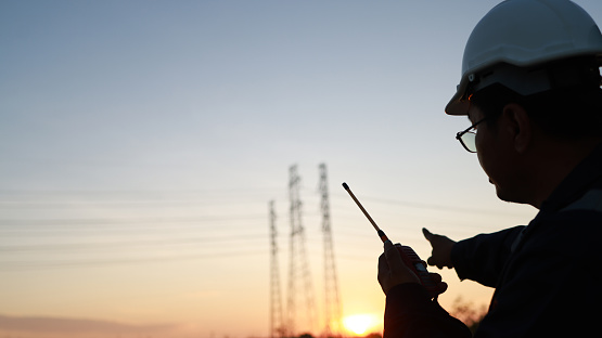 Silhouette Senior Electrical engineer with safety uniform using walkie talkie command and communication on the job