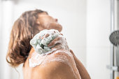Woman washing with bath sponge in shower