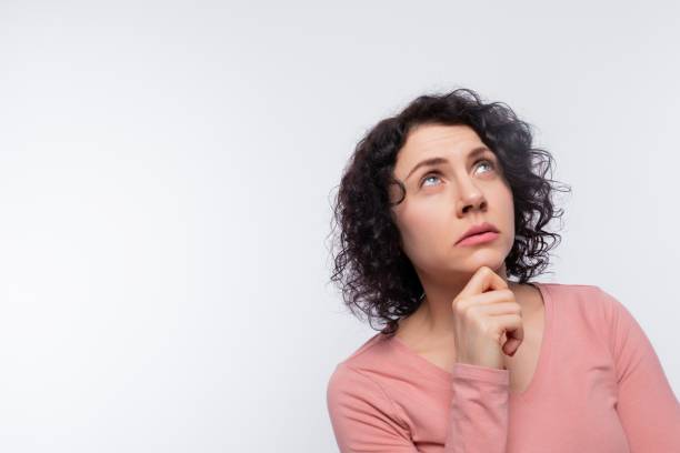 istock Brunette with curled hair thinks and looks up, studio photo from copy space 1885871583