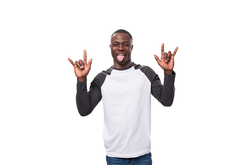 young stylish confident american man dressed casually in a black and white sweatshirt with long sleeves makes a grimace and shows his tongue.