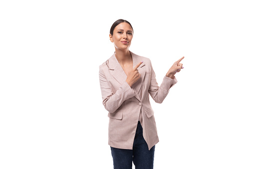 A cute young woman with black hair dressed in a beige jacket and jeans tells interesting news.