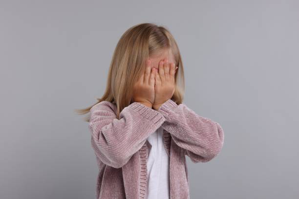 istock Resentful girl covering face with hands on grey background 1885897458