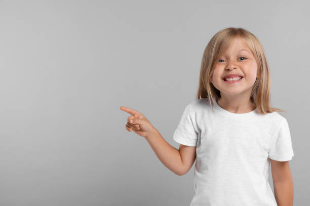 istock Special promotion. Smiling girl pointing at something on grey background. Space for text 1885897993