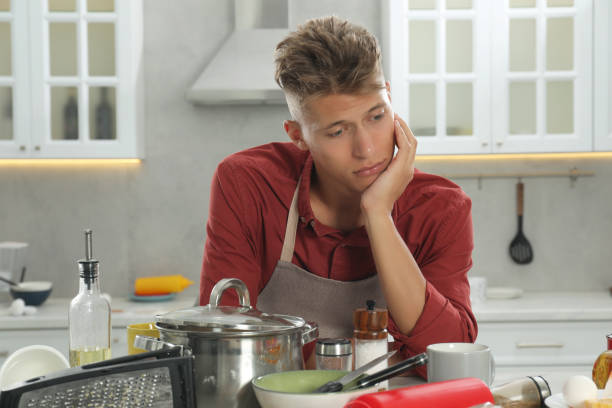istock Upset man in messy kitchen. Many dirty dishware and utensils on table 1885898274