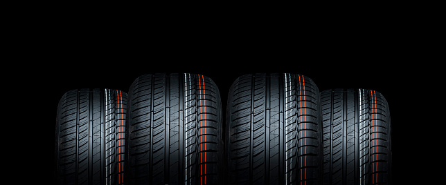 Four tires treads isolated on black background. Car maintenance for safety. Copy space for commercial advertising flyer or leaflet for workshops.
