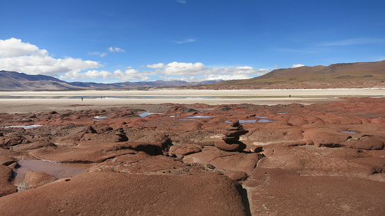 Red Rocks (Piedras Rojas), lagoon and salt flats with unrecognizable tourists in Atacama Desert, Chile. These volcanic landscapes are situated in the heart of the Chilean altiplano. Travel destination South America background with copy space.